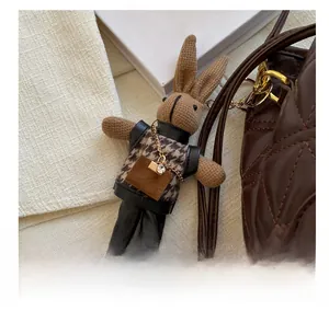 Detail of cute knitted bunny bag charm wearing houndstooth vest and black leather pants