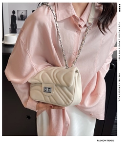 Detail of cream quilted crossbody bag with V-stitch pattern and silver twist lock closure