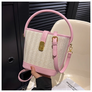 Close-up of pink leather trim and beige woven texture on stylish straw bucket bag