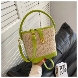 Detailed close-up of lime green woven straw bucket bag with gold square buckle and handle