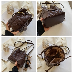 Detail view of brown quilted bucket bag with gold hardware and cute rabbit charm pendant