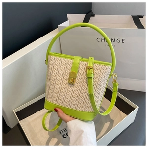 Detailed close-up of woven straw bucket bag with lime green leather trim and gold lock