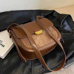Sacoche vintage marron avec boucle dorée posée sur une veste en cuir noir