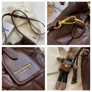 Detail of dark brown quilted leather bag featuring gold hardware and rabbit charm