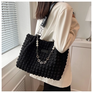 Detail of black bubble texture tote bag featuring pearl and silver floral chain ornament