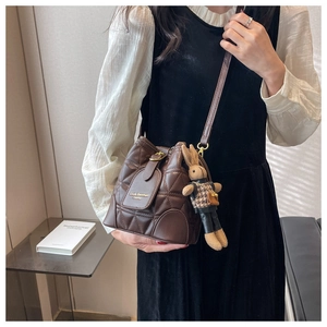 Brown quilted bucket bag detail with branded logo and a cute knitted rabbit pendant