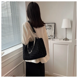 Detail of black bubble texture tote bag featuring elegant pearl and metal chain straps