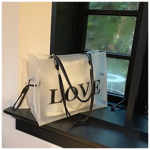 Close-up of semi-transparent tote bag featuring a black LOVE print and stitched leather straps