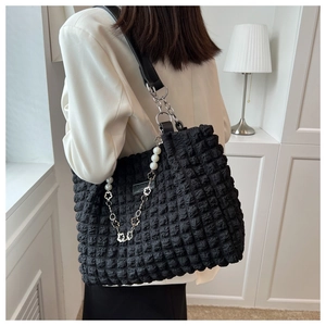 Close-up of black bubble textured tote bag with pearl and floral chain detail