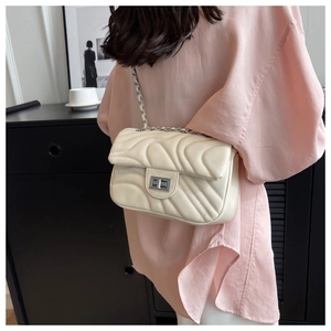 Detail of off-white quilted crossbody bag with silver twist lock and chain strap