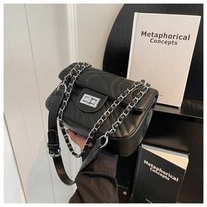 Detail of black quilted crossbody bag with silver metal swivel lock and chain strap