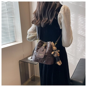 Detail of dark brown quilted bucket bag with drawstring and rabbit plush pendant charm