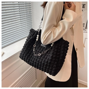 Detail of black waffle-textured tote bag with pearl and floral silver chain strap decoration