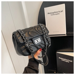 Detailed macro view of black quilted faux leather handbag with silver chain and metal lock
