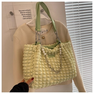 Detailed shot of the popcorn texture fabric and large pearl charm on the light green tote