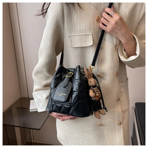 Detail of black quilted bucket bag with gold logo and cute plush rabbit charm