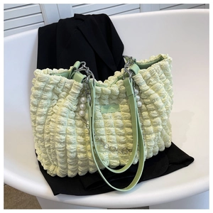 Macro shot of light green bubble texture handbag with pearl chain and leather strap