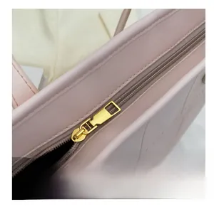 Close-up of smooth gold-tone metal zipper on a premium pink leather tote bag