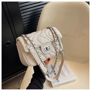Detail of off-white quilted crossbody bag with wave pattern stitching and silver twist lock