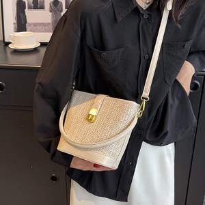 Chic woven bucket bag with gold lock and adjustable strap worn by a model