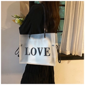 Detail of a large frosted transparent tote bag with LOVE logo and black shoulder straps