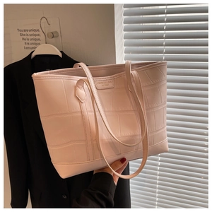 Detail shot of pink crocodile pattern tote bag featuring metallic brand plate on PU leather