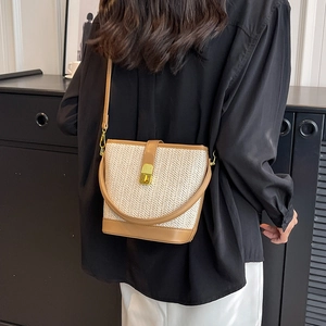 Women's woven straw bucket bag with brown leather trim and golden metal clasp for summer
