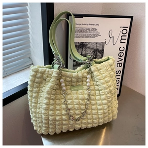 Detail of light yellow bubble texture tote bag with pearl and floral metal chain accessory