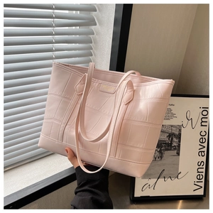Close-up of pink faux leather tote bag with crocodile texture and gold logo detail