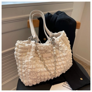 Detail of cream puff textured tote bag with elegant pearl chain and silver hardware