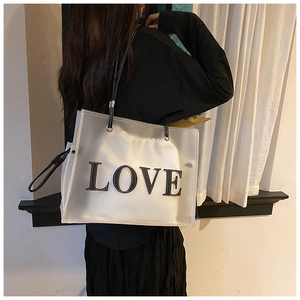 Detail of transparent PVC tote bag with LOVE patch and white drawstring liner bag