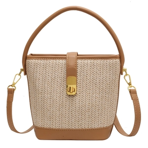Women's woven straw bucket bag with brown leather trim and golden metal clasp