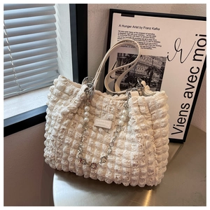 Detail of off-white bubble texture tote bag with pearl chain and fashion label
