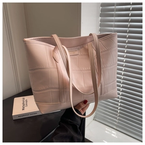 Close-up of pink tote bag with crocodile texture and branded metal tag detail