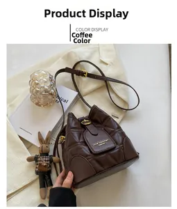 Detail of brown quilted bucket bag with gold logo, drawstring, and bunny charm on soft knit