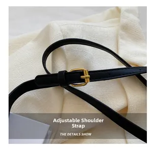 Detail of adjustable black leather shoulder strap with rectangle golden metal buckle