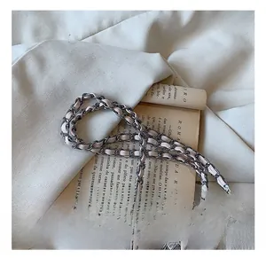 Detailed macro view of refined metal chain woven with pink leather strap on a designer bag