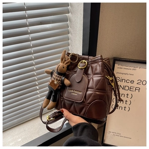 Close-up of brown quilted leather bucket bag with metal buckle and rabbit charm detail
