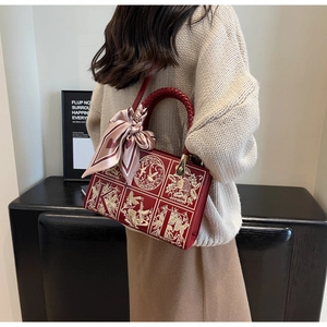 Detailed embroidery of gold floral patterns on red leather bag with silk scarf accessory