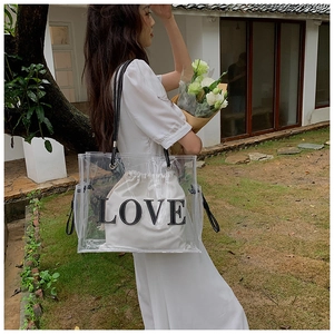 Detailed outdoor view of a transparent PVC tote bag featuring a 'LOVE' drawstring inner pouch
