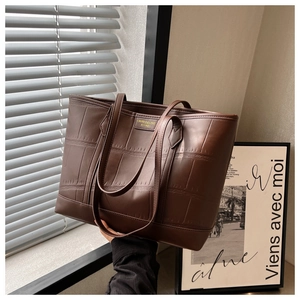 Detail of dark brown faux crocodile leather tote bag with elegant gold logo nameplate