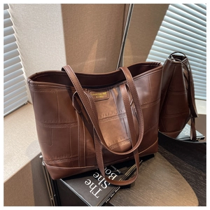 Detailed view of dark brown tote bag with crocodile pattern and metallic logo plate