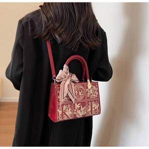 Detail of red leather tote bag with gold embroidery, woven handle and silk scarf