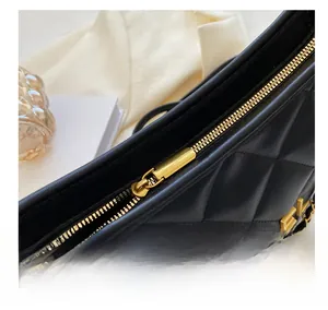 Detail shot of black quilted bag featuring golden HNGEL logo and sleek metal zipper