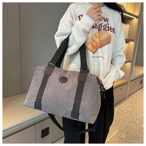 Detail view of large gray canvas travel tote bag with reinforced handles and logo patch