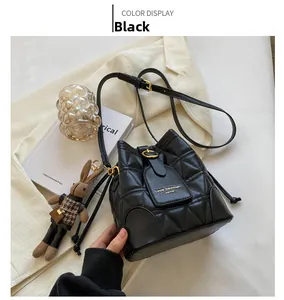 Detail of black quilted bucket bag with gold hardware and a cute rabbit doll charm