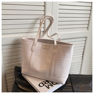 Detail view of large cream tote bag with crocodile texture and thin shoulder straps