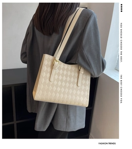 Detail of cream quilted tote bag featuring fine diamond pattern and gold buckle strap