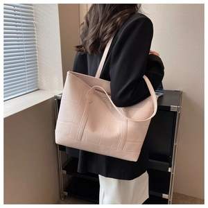 Close-up of light pink tote bag with crocodile texture and double shoulder straps