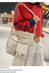 Detail of white Oxford tote bag featuring letter embroidery and front pockets for storage